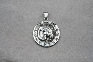 Macro view of vintage silver zodiac pendant featuring engraved ram and Chinese symbols