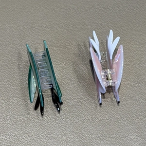 Detail view of swallow bird hair claws in pink and green colors on leather surface