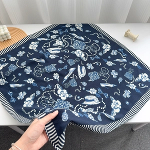 Detail of navy silk scarf featuring camellia and pearl prints with striped borders