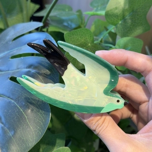 Detail of a bird-shaped swallow hair claw clip in emerald green with pearl texture finish