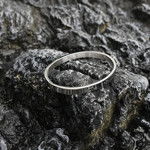 Minimalist silver oval titanium steel bangle with a polished mirror finish on dark rock