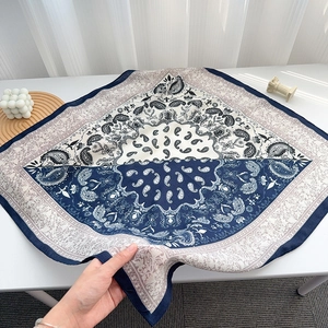 Detail eines blau-cremefarbenen Paisley-Musters auf einem quadratischen Seidenschal