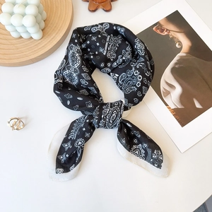 Detail of classic black paisley silk scarf with a knotted design and white rolled edges