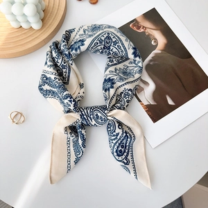 Detailed close-up of paisley pattern silk scarf with a minimalist lifestyle backdrop