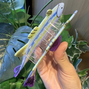 Detail of colorful trout hair claw clip featuring transparent acrylic fish shape and yellow fins