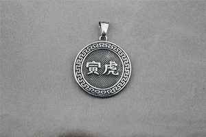 Close-up of silver steel zodiac pendant with tiger character and fretwork border