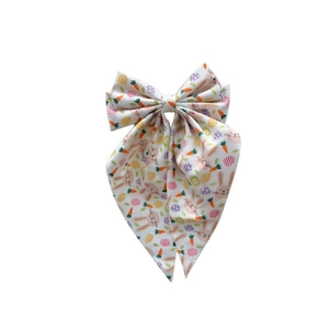 Close-up of Easter bow hair clip with cartoon rabbit, carrot and egg prints on white fabric