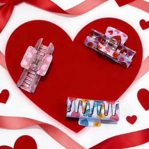 Three square hair claws with colorful hearts on red velvet heart background