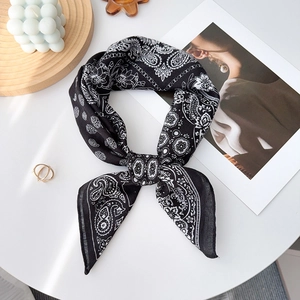 Detail of black and white paisley silk scarf tied in a bow on a minimalist desk