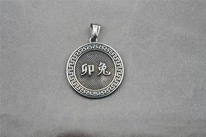 Detail of silver zodiac pendant with Rabbit character and Greek fret pattern on edges
