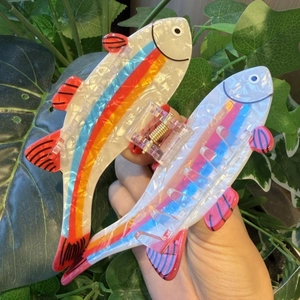 Detailed macro view of two colorful trout-shaped hair claws with vibrant striped patterns