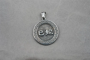 Detail of vintage silver snake zodiac pendant with Greek meander pattern and textured finish