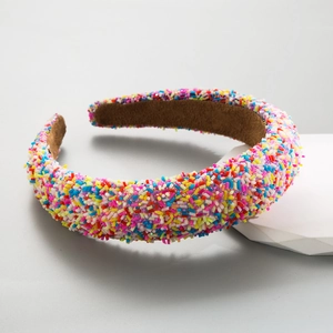 Colorful sprinkle decorated wide sponge headband on minimalist geometric display base