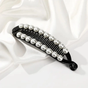 Detailed view of banana hair clip with white pearls and rhinestones on satin