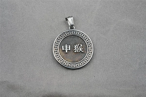 Macro detail of silver stainless steel zodiac pendant featuring engraved monkey symbol