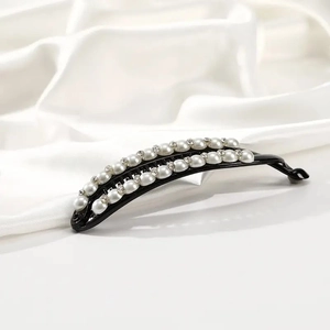 Detail of banana hair clip with white pearls and sparkling rhinestones on black acrylic