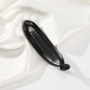 Macro detail of black matte banana hair clip showing secure inner teeth on silk fabric