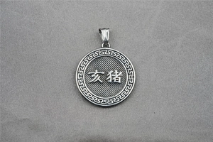 Macro view of a round silver steel pendant with Chinese Pig Zodiac and Greek pattern