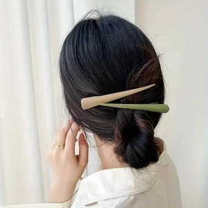 Close-up of beige and green matte hair clips on dark hair showing elegant styling