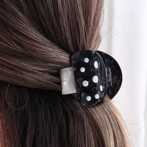 Detail of mushroom acetate hair claw in black polka dot pattern on dark hair