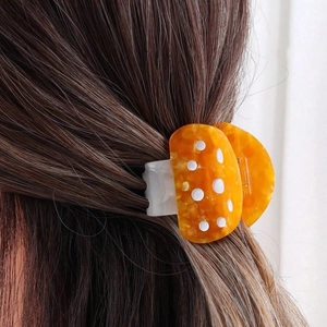 Detail of orange mushroom hair claw clip with white dots on brunette hair