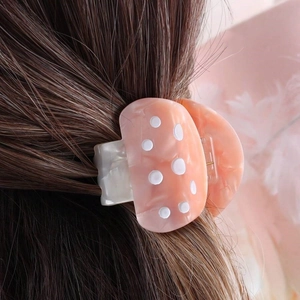 Macro detail of a mushroom-shaped acetate hair clip with pink marble and white dots
