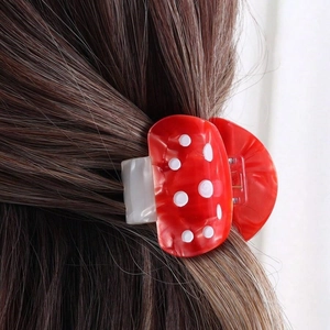 Detail of red polka dot acetate hair claw clip styled on long brown hair for women