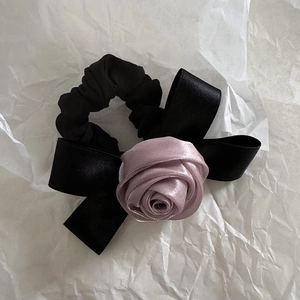 Détail d'une rose en satin et d'un nœud noir sur un chouchou vintage pour cheveux