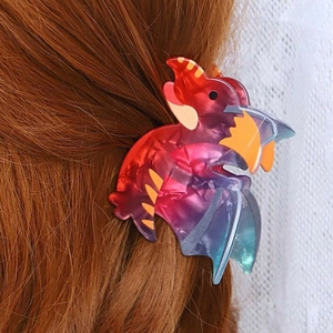 Close-up of a gradient acetate dinosaur hair claw clip securing a ponytail on long hair