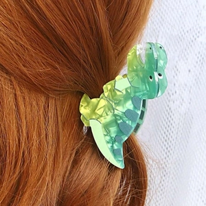 Detail of green dinosaur acetate hair claw clip showing marble texture on brown hair