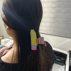 Détail d'une pince à cheveux en forme de crayon fixant une queue-de-cheval de dos