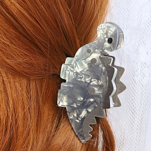 Macro shot of grey marble acetate dinosaur hair clip styled on auburn wavy hair