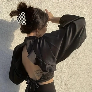 Detail einer Schachbrett-Haarklammer bei einer Frau im rückenfreien Satin-Top