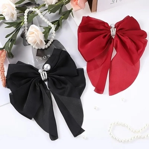 Detail view of pearl-embellished bow hair clips in elegant black and dark red satin ribbon