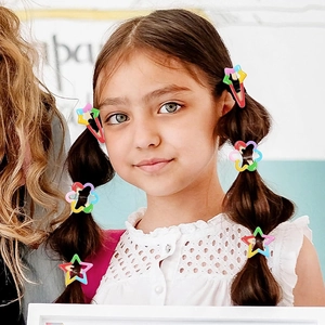 Close-up of a child wearing rainbow star and flower hair clips in a ponytail style
