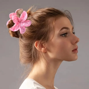 Pince à cheveux fleur frangipanier rose avec motif marbre sur profil de modèle