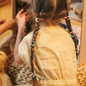 Close-up of a child wearing colorful star and flower hair clips on a braided hairstyle