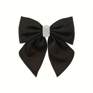 Détail de la pince à cheveux nœud en satin noir avec boucle élégante en strass