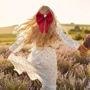 Elegant red satin bow hair clip with pearl center on model in lavender field