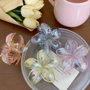 Pinces à cheveux en forme de fleur irisées en quatre couleurs sur une table en bois