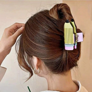 Pince à cheveux créative en forme de crayon jaune portée sur une coiffure brune