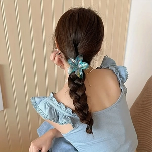 Pince à cheveux fleur turquoise irisée présentée sur une coiffure tressée