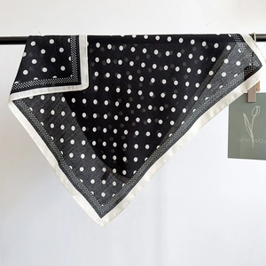 Detailed close-up of a black and white polka dot silk scarf hanging with natural drape