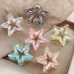Détail de six pinces à cheveux étoiles irisées de couleurs variées sur un plateau