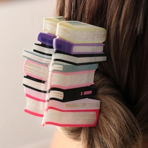 Macro detail of the colorful book-shaped acetate hair claw clip worn on long brown hair