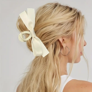 Detail of a large cream bow hair claw clip styled on blonde hair for a minimalist look