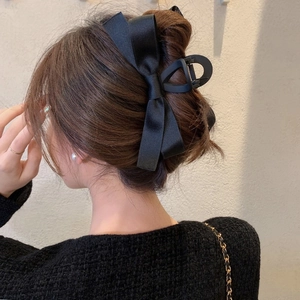 Detail shot of a black satin double-layered bow hair claw clip for elegant hairstyles