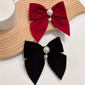 Velvet bow hair clips with pearl pendants in red and black on a wooden tray