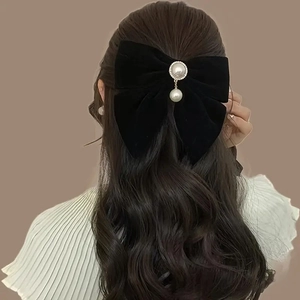 Elegant black velvet bow hair clip with pearl pendant on brown wavy hair for wedding