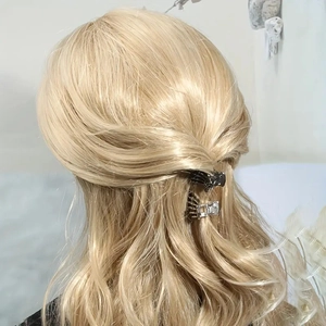 Detail von silbernem Strass und schwarzer Metallhaarklammer auf blondem Haar